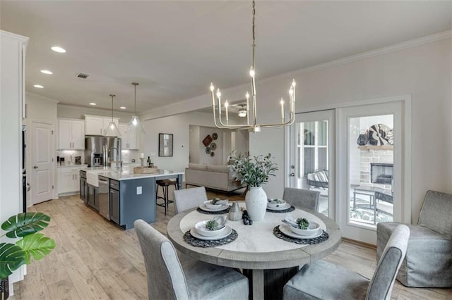 dining area with crown molding, a chandelier, and light hardwood / wood-style floors