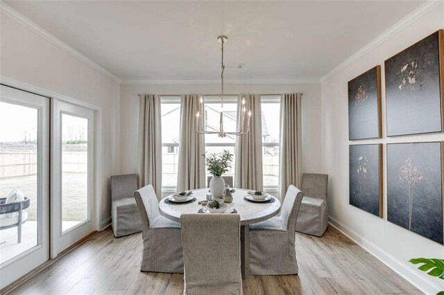 dining space featuring crown molding, an inviting chandelier, and light hardwood / wood-style floors