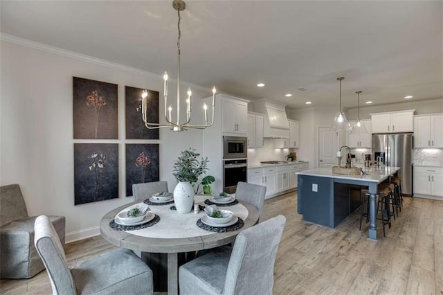 dining room with crown molding, sink, a notable chandelier, and light wood-type flooring