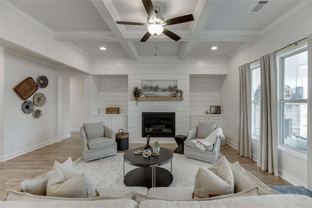 living room featuring coffered ceiling, beam ceiling, ornamental molding, a fireplace, and hardwood / wood-style floors