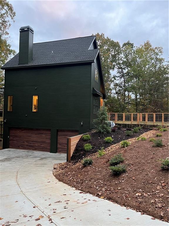 6 Huntington Pl, Dahlonega, GA 30533 - view of side of home featuring an attached garage, concrete driveway, a chimney, fence, and roof with shingles