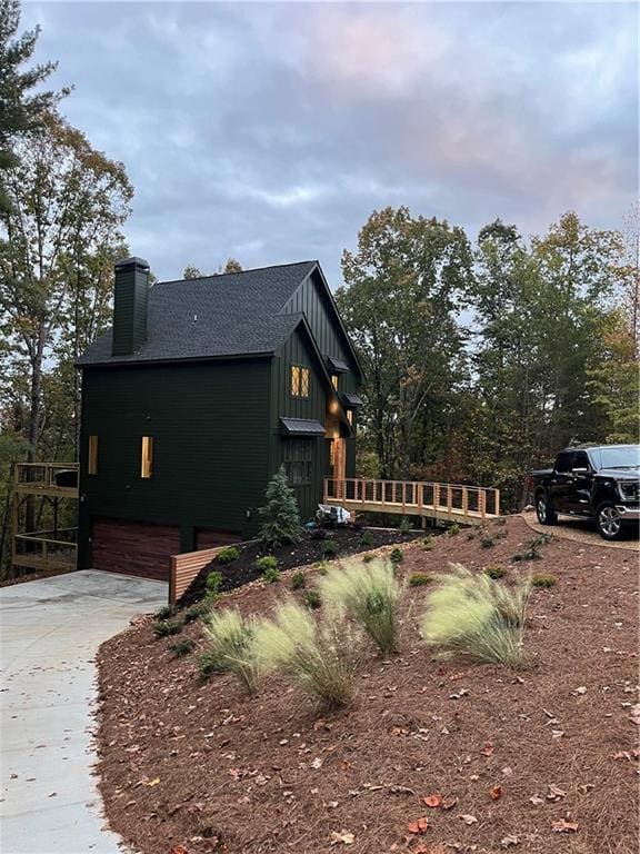 6 Huntington Pl, Dahlonega, GA 30533 - view of side of home with a chimney, driveway, an attached garage, board and batten siding, and roof with shingles