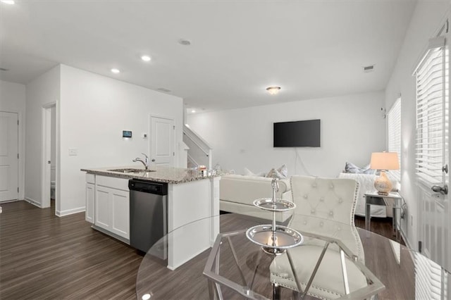 kitchen featuring dark hardwood / wood-style flooring, an island with sink, stainless steel dishwasher, and sink