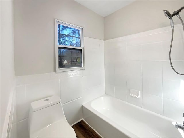 bathroom featuring hardwood / wood-style floors, toilet, tile walls, and shower / tub combination