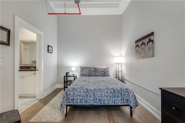 bedroom featuring wood finished floors, connected bathroom, and baseboards