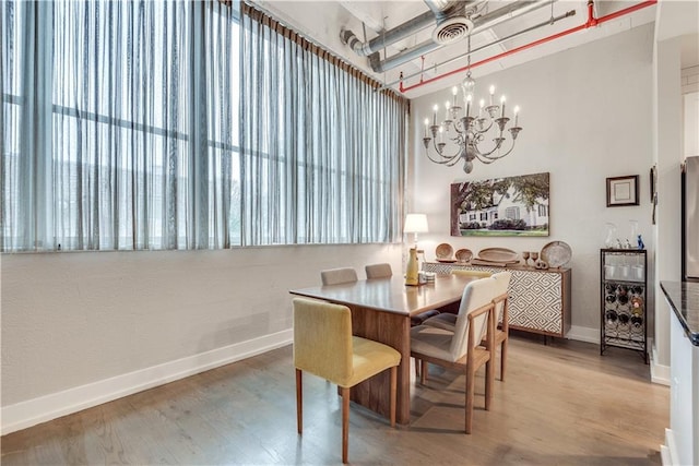 dining room with baseboards, visible vents, a chandelier, and wood finished floors