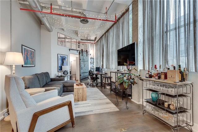 living room featuring wood finished floors, visible vents, a high ceiling, and a barn door