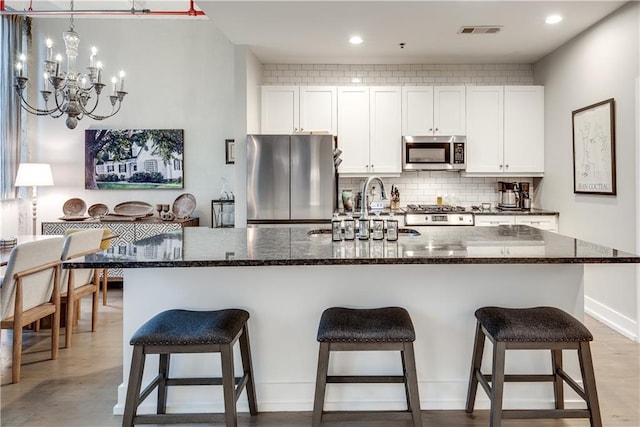 kitchen with stainless steel appliances, white cabinetry, a center island with sink, and visible vents