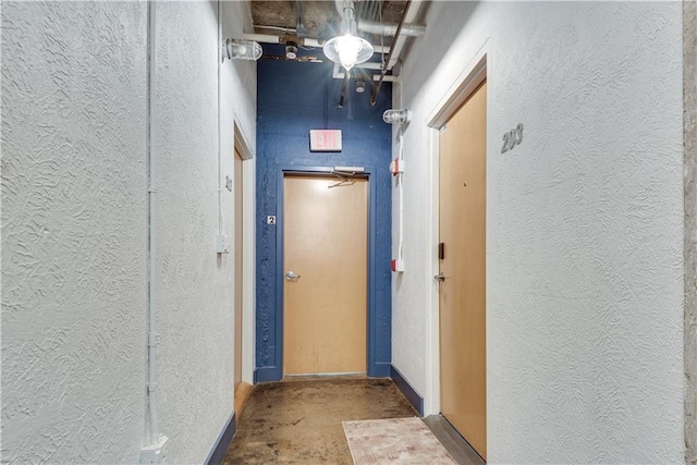 hallway featuring concrete floors and a textured wall