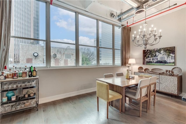 dining area with a chandelier, wood finished floors, visible vents, and baseboards