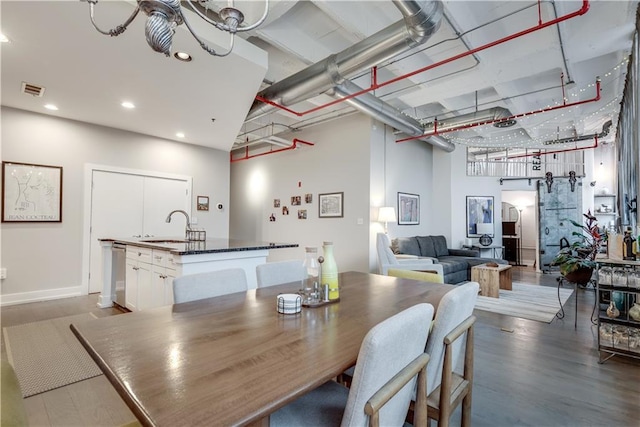 dining room featuring recessed lighting, visible vents, a towering ceiling, a barn door, and wood finished floors