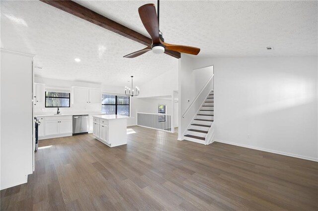 unfurnished living room featuring dark wood-type flooring, ceiling fan with notable chandelier, a textured ceiling, stairway, and vaulted ceiling with beams