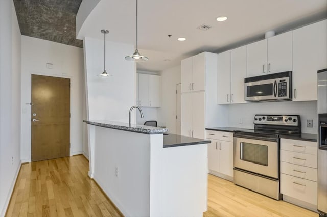 943 Peachtree St NE Unit 716, Atlanta, GA 30309 - kitchen with stainless steel appliances, light wood-style flooring, white cabinets, decorative light fixtures, and recessed lighting