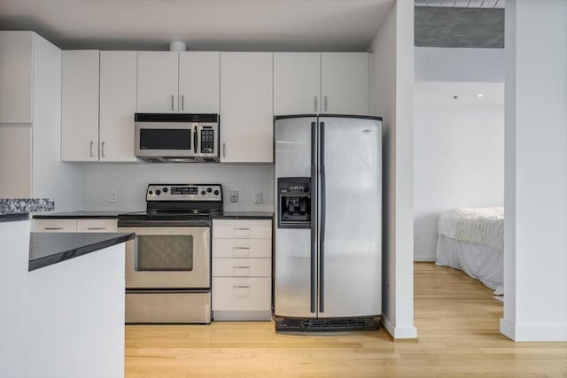 943 Peachtree St NE Unit 716, Atlanta, GA 30309 - kitchen with appliances with stainless steel finishes, light wood-style flooring, baseboards, and dark countertops