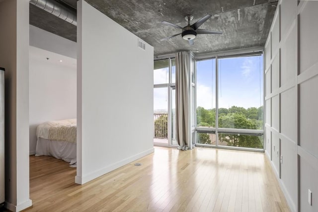 943 Peachtree St NE Unit 716, Atlanta, GA 30309 - empty room with floor to ceiling windows, light wood-style flooring, a ceiling fan, and baseboards