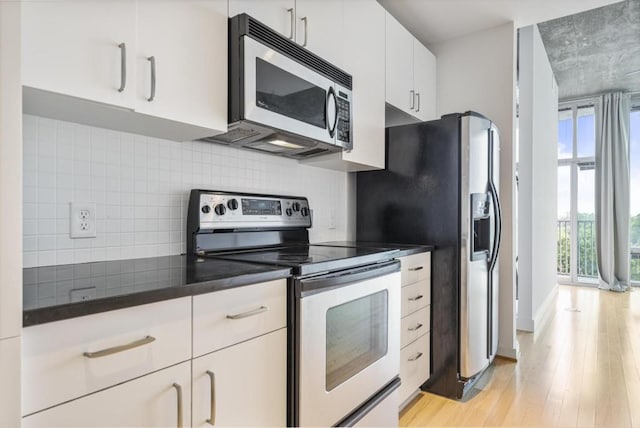 943 Peachtree St NE Unit 716, Atlanta, GA 30309 - kitchen featuring stainless steel appliances, decorative backsplash, light wood finished floors, and dark countertops