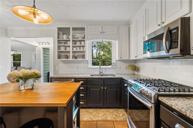 kitchen with light stone counters, stainless steel appliances, sink, white cabinetry, and light tile patterned flooring