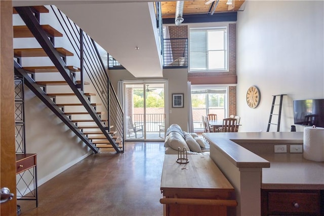 living room featuring a high ceiling, wood ceiling, and concrete floors