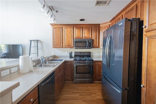 kitchen with hardwood / wood-style floors, appliances with stainless steel finishes, kitchen peninsula, and sink