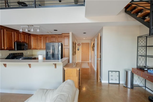 kitchen with black appliances, kitchen peninsula, and a kitchen breakfast bar