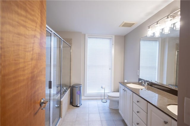 bathroom with vanity, a shower with shower door, tile patterned flooring, toilet, and a wealth of natural light