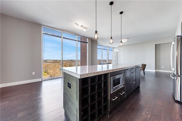 kitchen featuring dark wood-style floors, appliances with stainless steel finishes, expansive windows, and dark cabinets