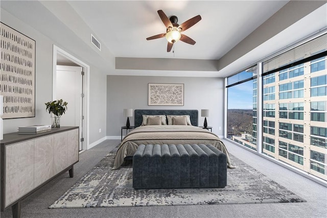 bedroom with carpet, a raised ceiling, visible vents, and baseboards