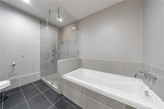 bathroom featuring toilet, a stall shower, a garden tub, and tile patterned floors