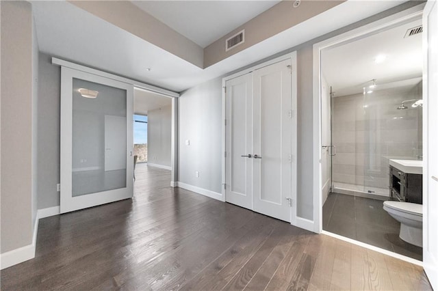 interior space with dark wood finished floors, visible vents, and baseboards