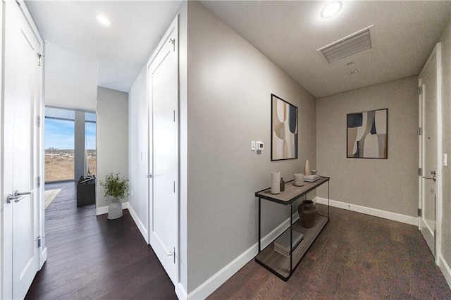 corridor featuring dark wood-style flooring and baseboards