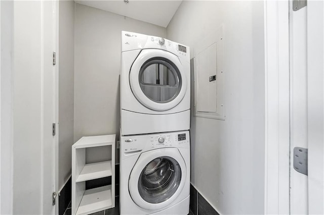 laundry room with laundry area, electric panel, and stacked washer / dryer