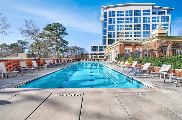 community pool with a patio and fence