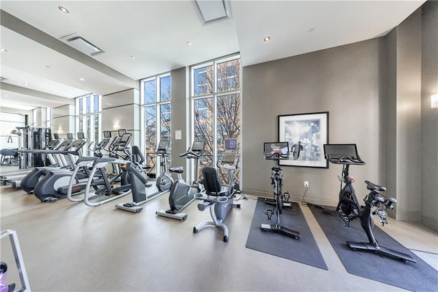 workout area with a wall of windows, visible vents, and recessed lighting