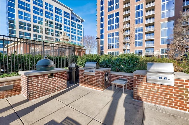 view of patio with area for grilling, a grill, and fence