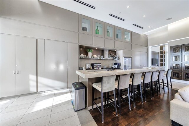 kitchen with a towering ceiling, a spacious island, modern cabinets, a breakfast bar, and built in fridge