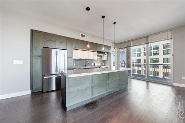 kitchen featuring dark wood finished floors, freestanding refrigerator, a wall of windows, light countertops, and backsplash