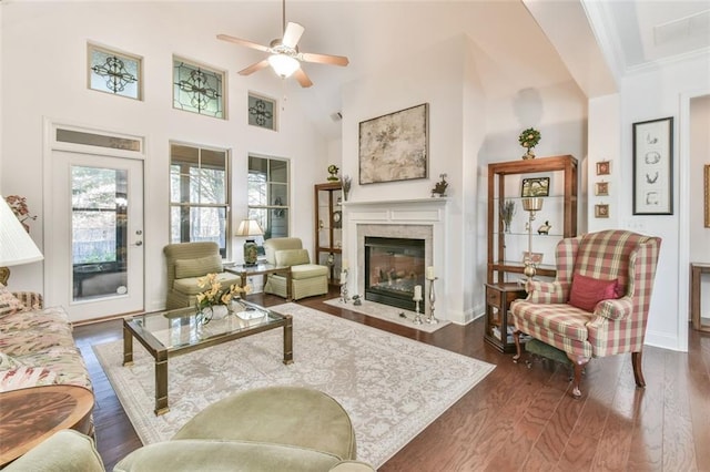 living room with ceiling fan, a towering ceiling, crown molding, and dark hardwood / wood-style floors