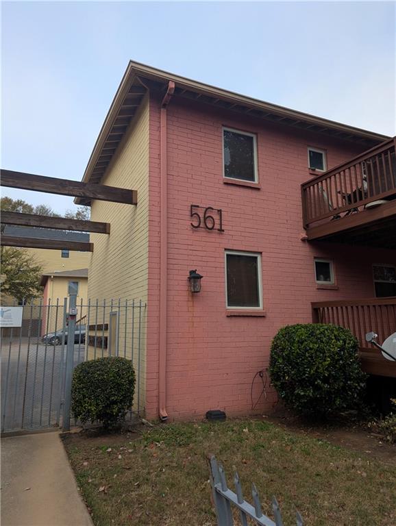 view of property exterior featuring brick siding, fence, and a balcony