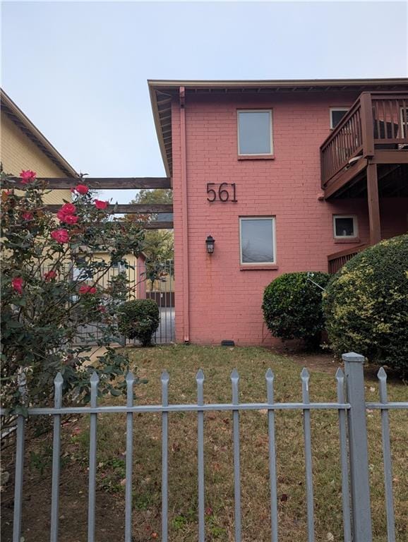 view of home's exterior featuring brick siding, fence, and a lawn