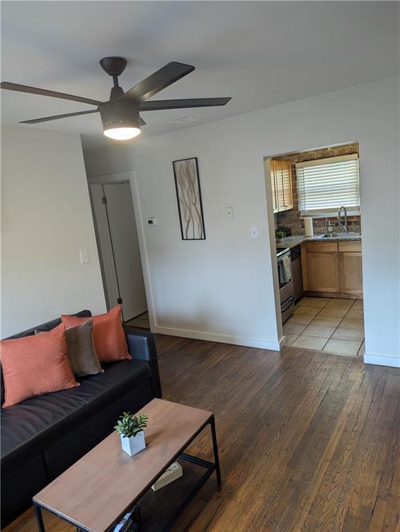 living area with ceiling fan, light wood finished floors, and baseboards