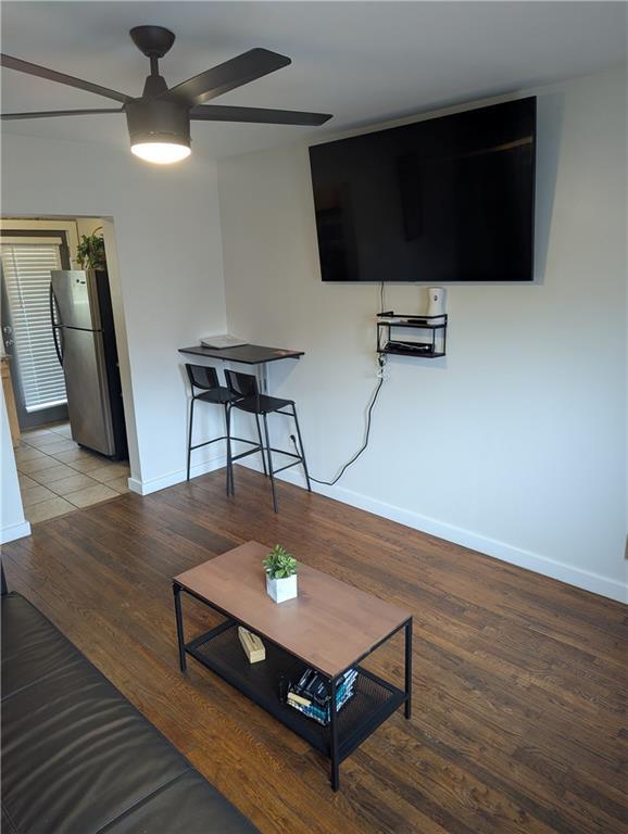 living area featuring baseboards, a ceiling fan, and wood finished floors