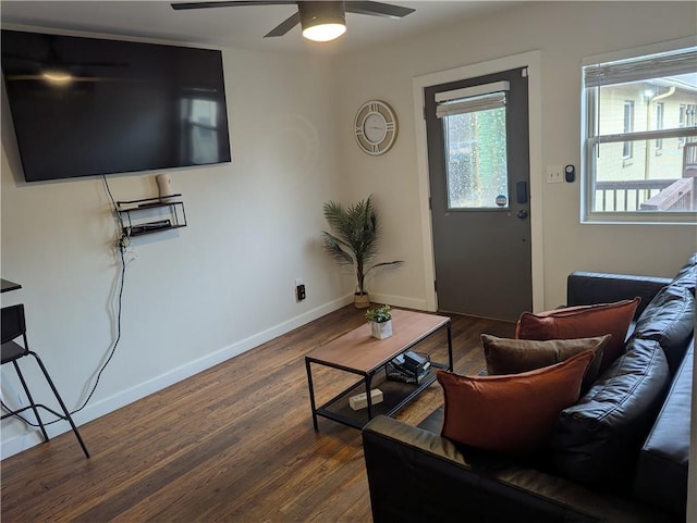 living room featuring ceiling fan, baseboards, and dark wood finished floors