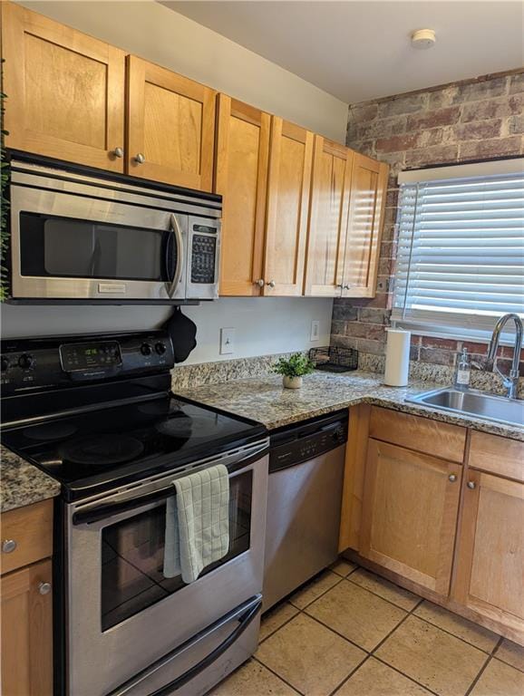 kitchen featuring light stone countertops, appliances with stainless steel finishes, a sink, and light tile patterned flooring