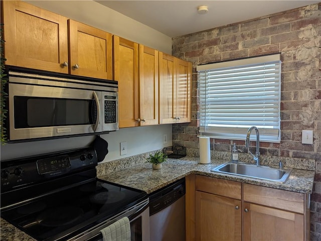 kitchen with appliances with stainless steel finishes, a sink, and light stone countertops