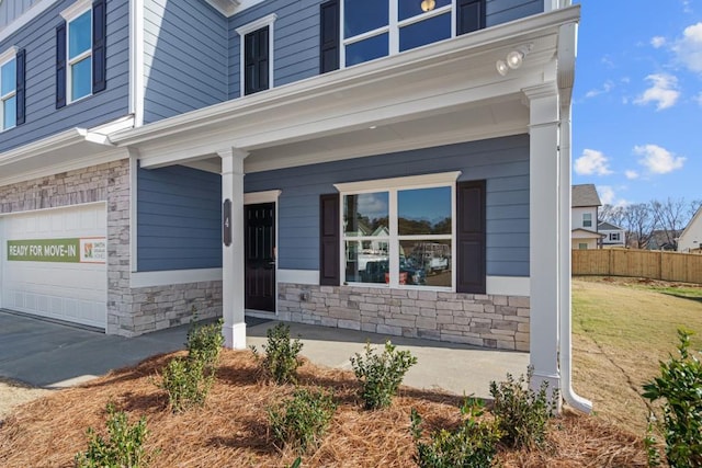 view of exterior entry with covered porch, a garage, and a lawn