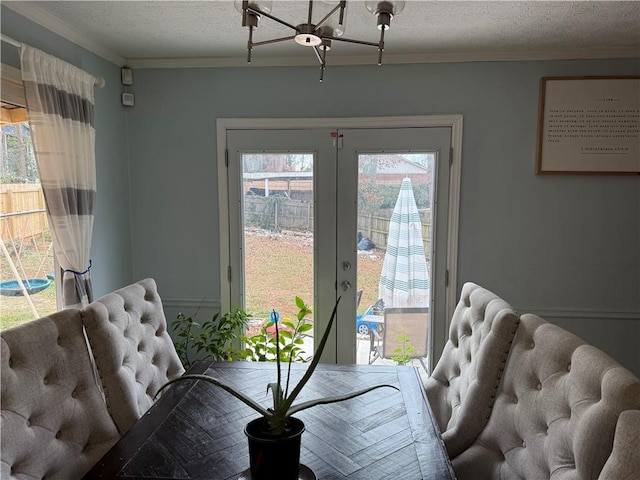 dining area with french doors, ornamental molding, and a textured ceiling