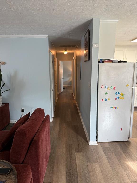 corridor with crown molding, a textured ceiling, and light hardwood / wood-style flooring