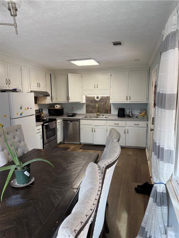 kitchen with white cabinetry, sink, stainless steel appliances, dark wood-type flooring, and a textured ceiling