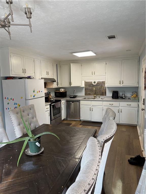 kitchen featuring stainless steel appliances, dark hardwood / wood-style floors, sink, and white cabinets