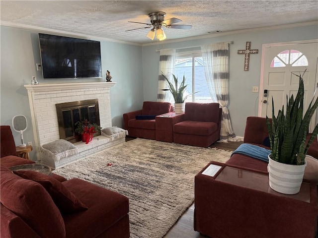 living room featuring wood-type flooring, a brick fireplace, a textured ceiling, and plenty of natural light